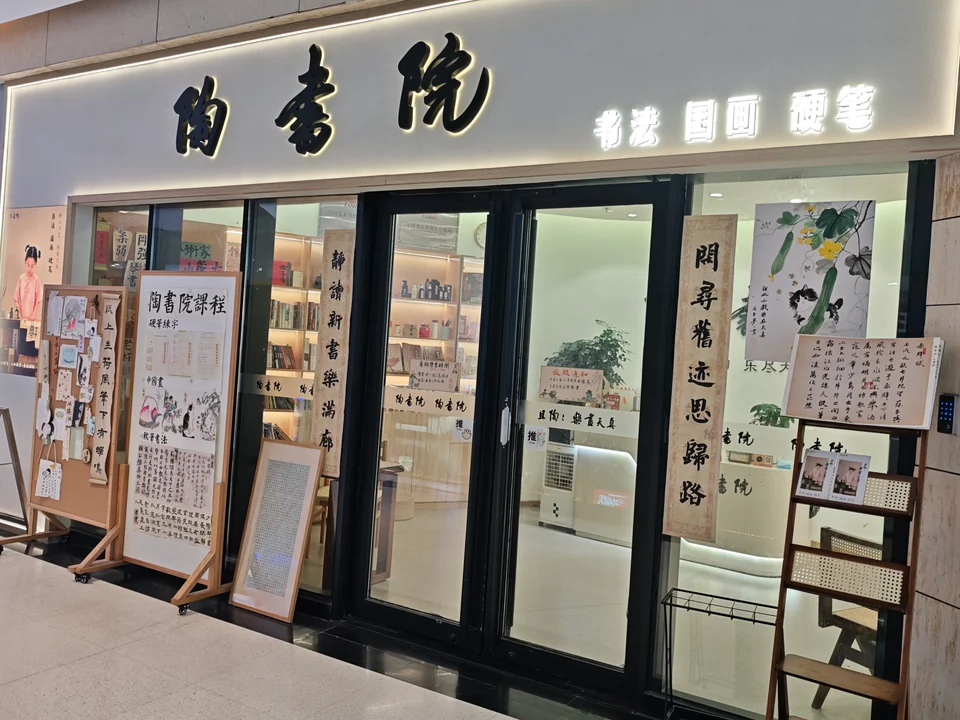 陶书院门面，发光招牌下是玻璃入口，两侧陈列书画与课程展示板
